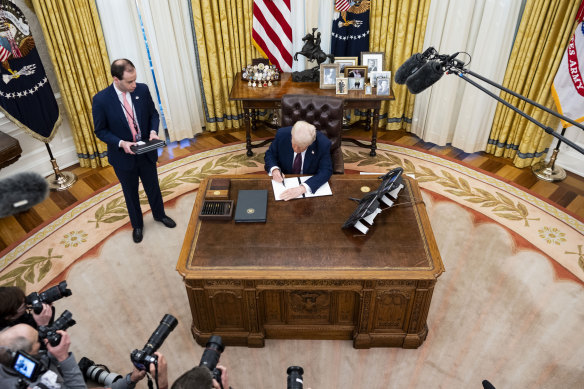 Donald Trump signs an executive order in the Oval Office.