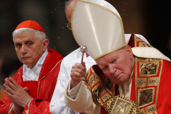 Then-cardinal Joseph Ratzinger looks at Pope John Paul II during a Mass in St. Peter’s Basilica in 2002.