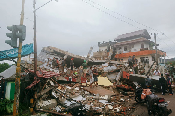 Residents inspect earthquake-damaged buildings in Mamuju, West Sulawesi, Indonesia, on Friday.