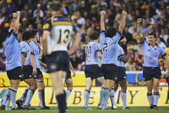 Brumbies captain Stirling Mortlock stands dejected as Waratahs players celebrate victory at Canberra Stadium in 2005.