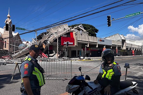 La polizia si riunisce davanti al fast food Jollibee crollato a causa del terremoto.