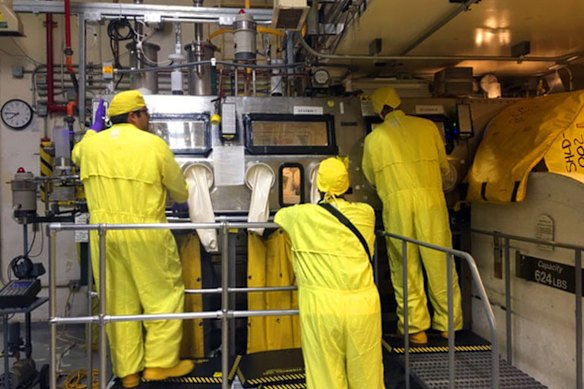 Lavoratori in equipaggiamento protettivo maneggiano rifiuti radioattivi al Los Alamos National Laboratory.