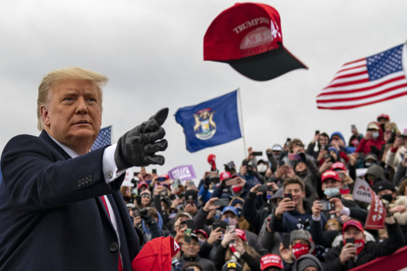 President Donald Trump tosses a cap during a campaign stop in Waterford Township, Michigan.