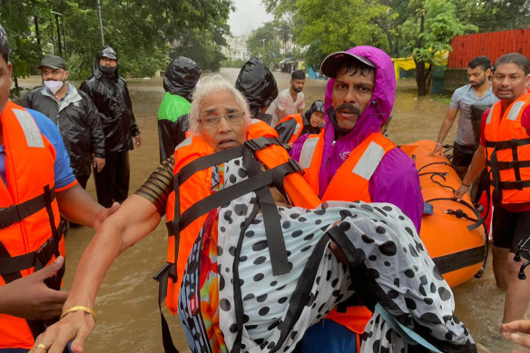 A National Disaster Response Force rescuer carries an elderly woman stranded in floodwaters in Kolhapur.