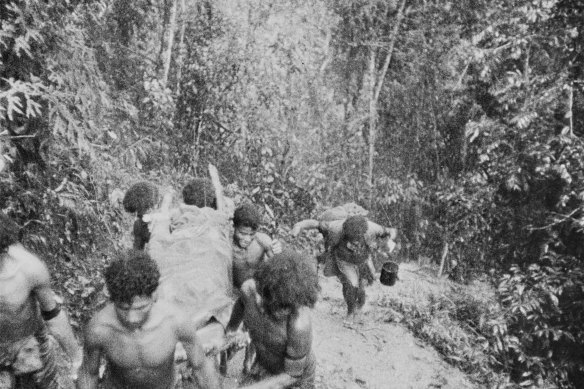 Papuan bearers (nicknamed the fuzzy-wuzzy angels) carry an Australian casualty through thick jungle at Eora Creek, 1942.