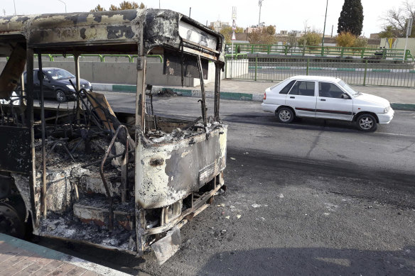 Cars in Tehran drive past a bus that was torched during protests that followed authorities' decision to raise petrol prices.