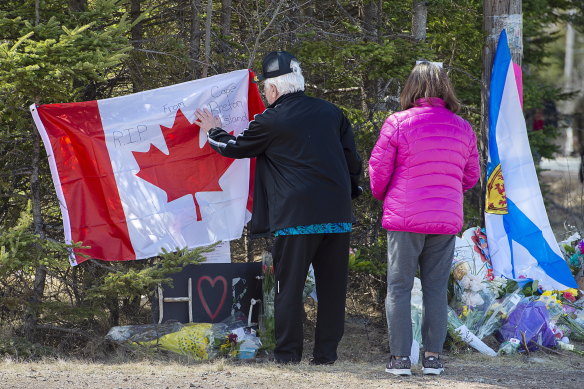Mourners place a flag at a memorial in Portapique, Nova Scotia, following the shooting rampage.