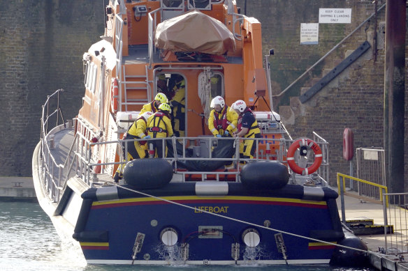 Members of the Dover lifeboat place a body bag on a stretcher after a large search and rescue operation launched in the Channel off the coast of Dungeness, in Kent.