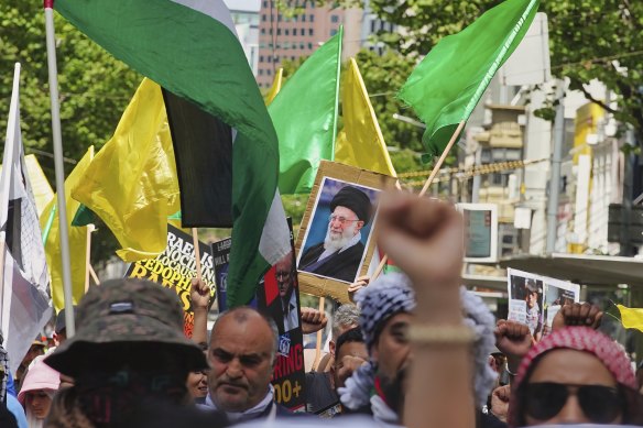 A protester in Melbourne holds up a portrait of Iranian leader Ali Khamenei.