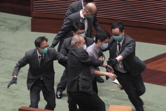 Pro-democracy lawmaker Ted Hui, centre, struggles with security personnel at the main chamber of the Legislative Council.