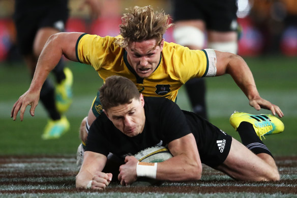 Over the top ... Michael Hooper dives in to tackle Beauden Barrett.