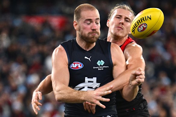 Harry McKay handballs while being tackled by Lachlan Blakiston.