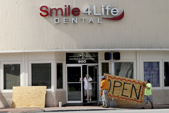 People at a business in the Normandy area in Miami Beach, Florida, remove the plywood shutters covering the front windows on Saturday, as Hurricane Dorian's latest track shows the storm has shifted east and north, increasing the possibility that the storm would not make landfall in Florida. 