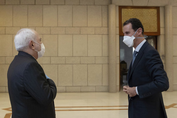 Syrian President Bashar al-Assad, right, wears a mask to help protect against the coronavirus as he speaks with Iranian Foreign Minister Mohammad Javad Zarif in Damascus in April.