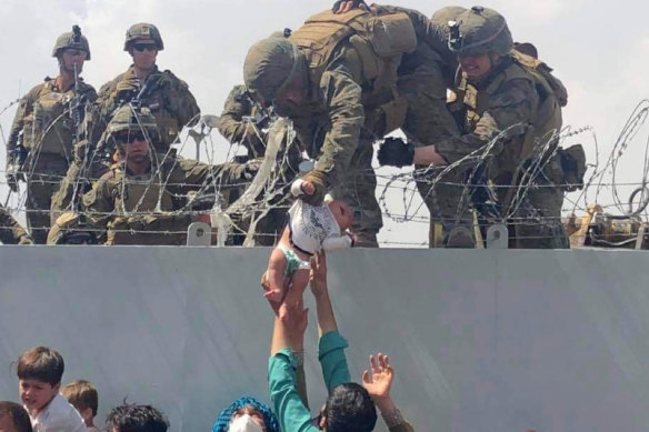 A baby is lifted by US soldiers across a wall at Kabul Airport in Afghanistan in the chaos that followed the takeover by the Taliban. Many families passed children over the barbed wire as they waited for days outside the gates. 