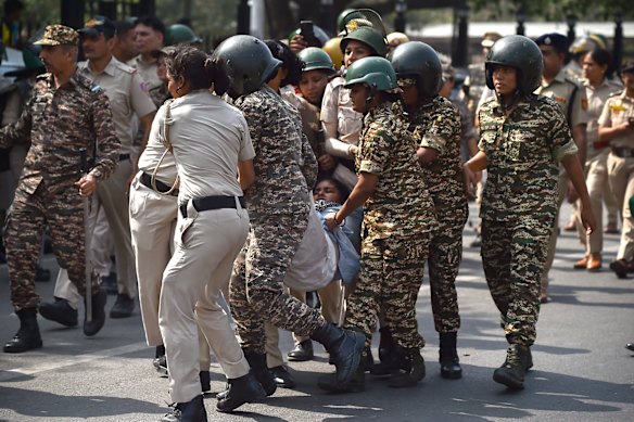 Police officers detain a protester.
