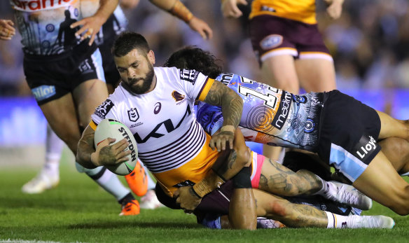 Broncos captain Adam Reynolds is grounded by Sharks defenders.