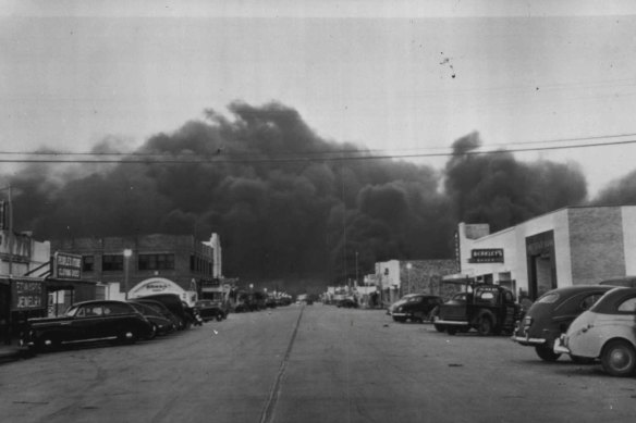 "Texas City Evacuated -- This view of a main street of this town shows only the automobiles of rescue and relief workers after all unnecessary people were evacuated to lessen the loss of life. The burning industrial area is in the extreme background. April 17, 1947."