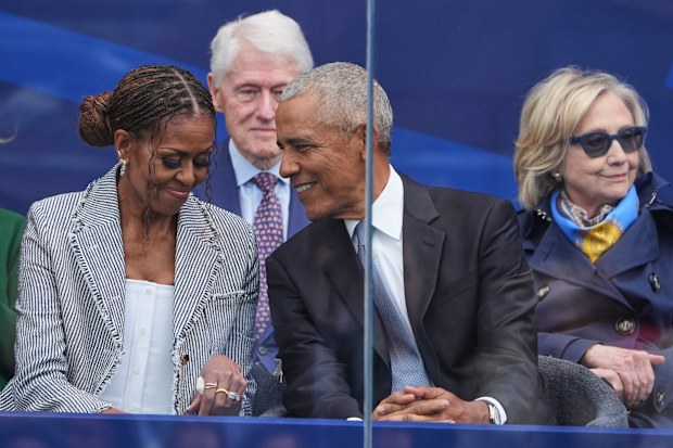 Michelle and Barack Obama speak to each other, with the Clintons sitting behind them.