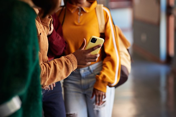 Generic shot of teens at school with phone