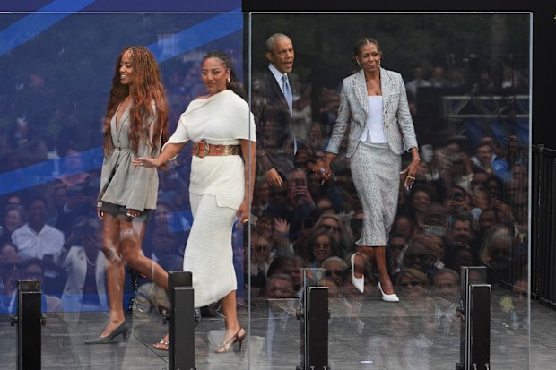 Former President Barack Obama, back center, and former first lady Michelle Obama, right, arrive on stage with their daughters, Sasha and Malia Obama
