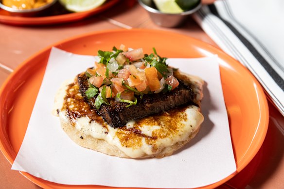 The brisket costra taco features a slab of smoked meat atop scorched cheese.