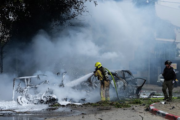 A firefighter works to extinguish vehicles set ablaze by fragments from the impact of an Iranian projectile in Tel Aviv, Israel.