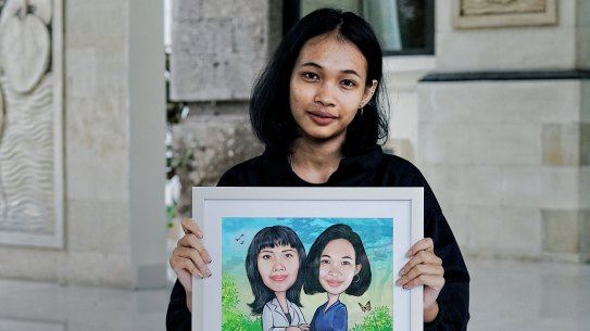 Dinda holds a newly finished artwork in which she was painted alongside her mother.