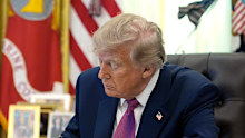 President Donald Trump signs an executive order in the Oval Office of the White House.