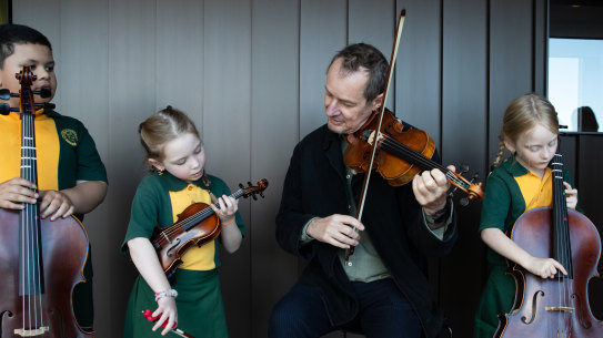 ACO artististic director Richard Tognetti with students from Marys North Public School. (L to R) TanginoaHalaifonua-Palu, 6, Ava Tuckwood, 6, Rebel Nordsven, 6 and Peyton Arecco, 7.  Story details:  a music program for students in low Socio-Economic Status (SES) schools run by ACO Foundations it is based on research showing that learning an instrument at a young age can improve the executive function of the brain. We’ve run it as a pilot program at St Marys North Public School in Western Sydney over the past 5 years, working closely with academics who have tracked the impact its had on the school and its students. 