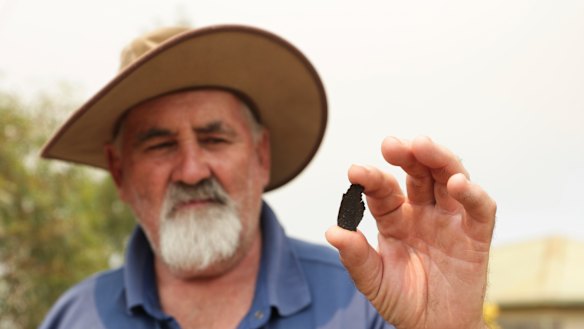 Bruthen resident Len Hooton holds up a burnt leaf blown onto his front yard.