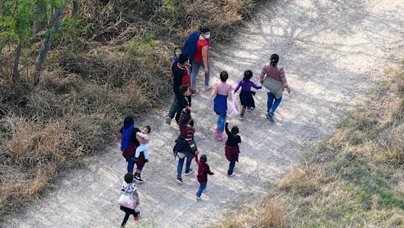 Migrants walk on a dirt road after crossing the US-Mexico border in Mission, Texas. 