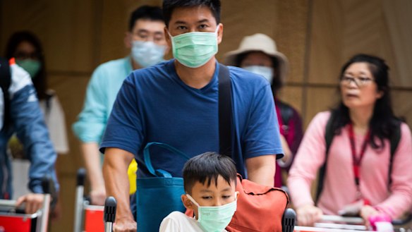 People arrive at Sydney Airport wearing masks to avoid contact with the coronavirus.