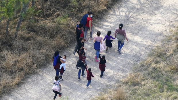 Migrants walk on a dirt road after crossing the US-Mexico border in Mission, Texas. 