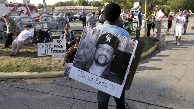 A protester carries a photograph of James Byrd jnr outside the Texas Department of Criminal Justice Huntsville Unit before the execution of Lawrence Russell Brewer in Huntsville, Texas in 2011.