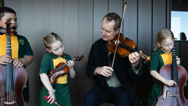 ACO artistic director Richard Tognetti with pupils from St Marys North Public School: (from left) Tanginoa Halaifonua-Palu, 6, Ava Tuckwood, 6, and Rebel Nordsven, 6, tune up before they play on Friday.