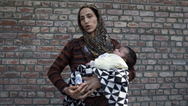 Kashmiri woman Ulfat holds her daughter as she waits outside a police station for news of her husband, who was detained during the night raids in Srinagar, Indian controlled Kashmir.