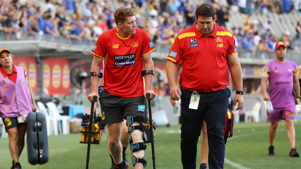 Gold Coast Sun Matt Rowell with coach Stuart Dew after injuring his knee at Optus Stadium.