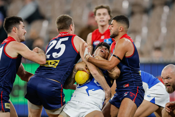 North’s Paul Curtis is tackled by Melbourne’s Tom McDonald (left) and Christian Salem.