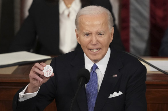 President Joe Biden holds up a Laken Riley button.