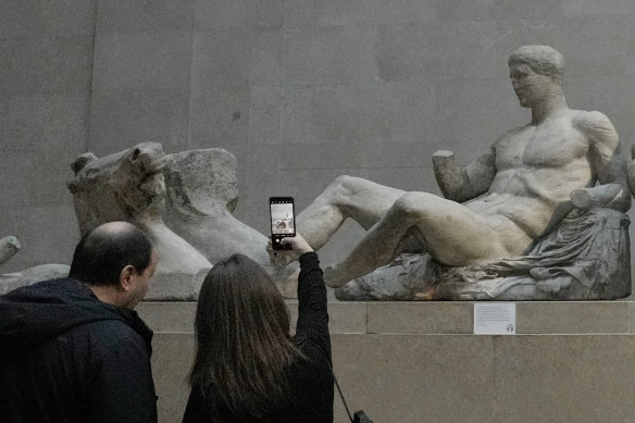 A visitor takes a picture of sculptures that are part of the Parthenon Marbles at the British Museum in London.