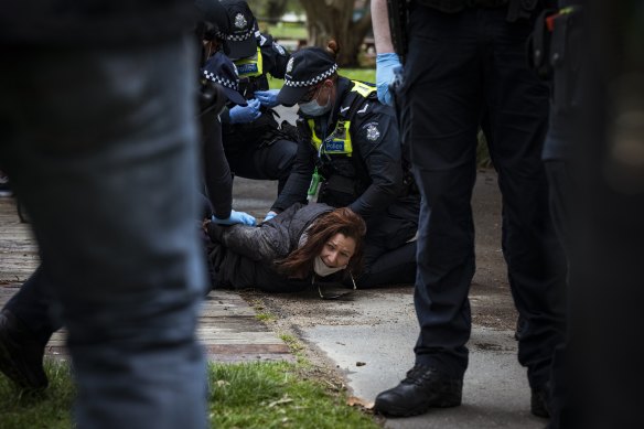 An anti-lockdown protester is arrested by police at Princes Park on Saturday. 