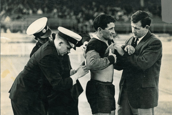 Orthopaedic surgeon Merv Cross treating a player on the field.