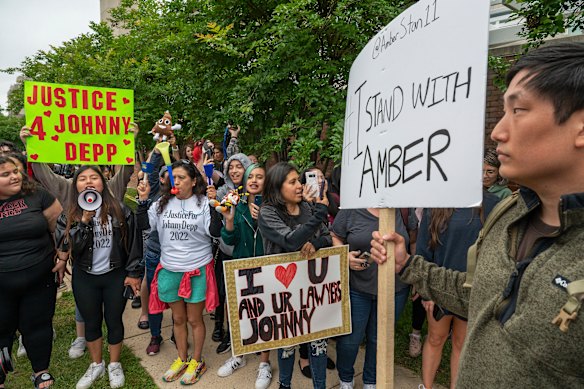 A man holds a placard backing Amber Heard as supporters of Johnny Depp rally outside court in Fairfax, Virginia, in 2022.