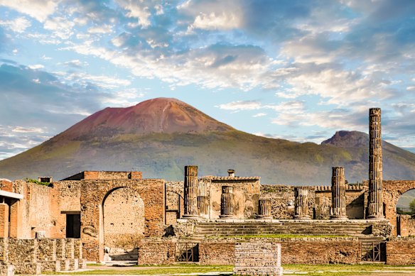 The volcano Vesuvius looms above the remains  of the Roman walls of Pompeii, Italy.