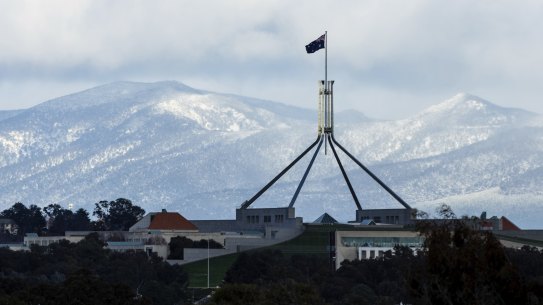 Parliament House in Canberra with snow on the mountains behind on Wednesday morning.