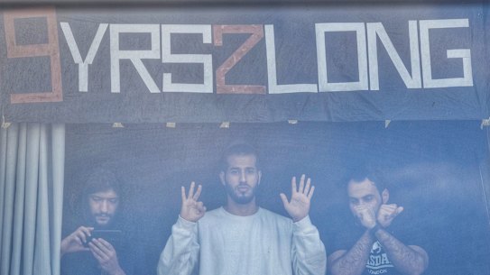 Refugees at the Park Hotel including Mehdi (left) watch the protests on the street during Djokovic’s detention. 