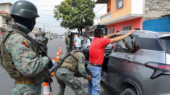 A soldier pats down a driver at a road block in Guayaquil, Ecuador.