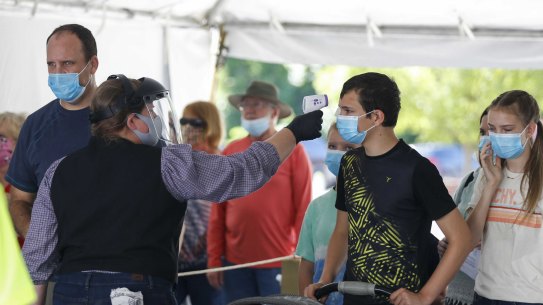 A Silver Dollar City employee takes the temperature of guests before they are allowed to enter the park near resort town of Branson, Missouri where authorities struggled to beat back a surge blamed on the fast-spreading Delta variant.