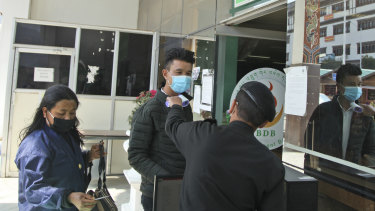 A security officer is taking the temperature of the people as a precaution against coronavirus in the capital Thimpu.
